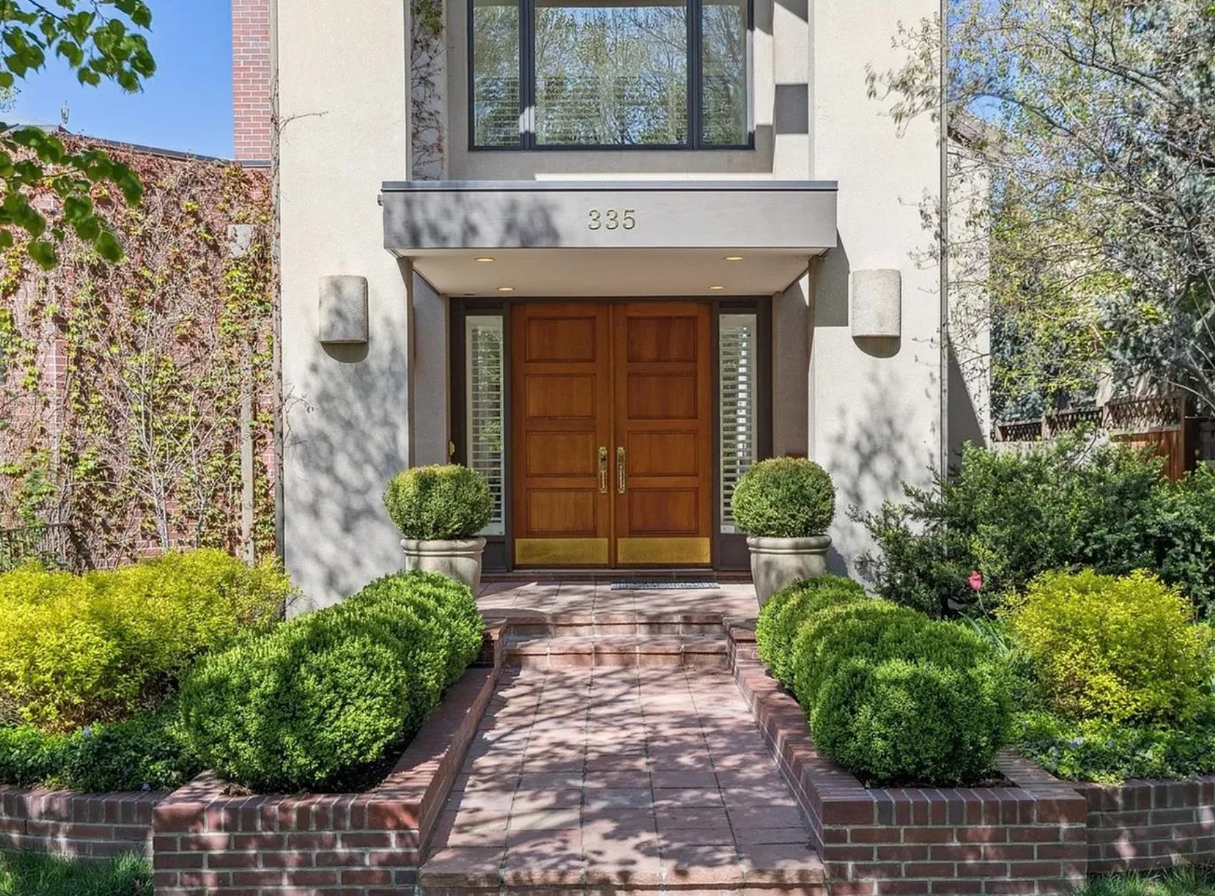Front entry of a Caliber custom home in Cherry Creek North with wood double doors and manicured landscaping