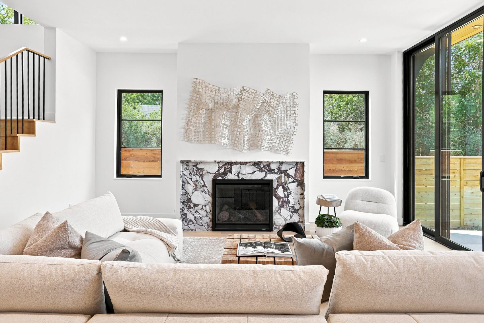 Living room of a Caliber custom home with a marble fireplace surround and white oak floors